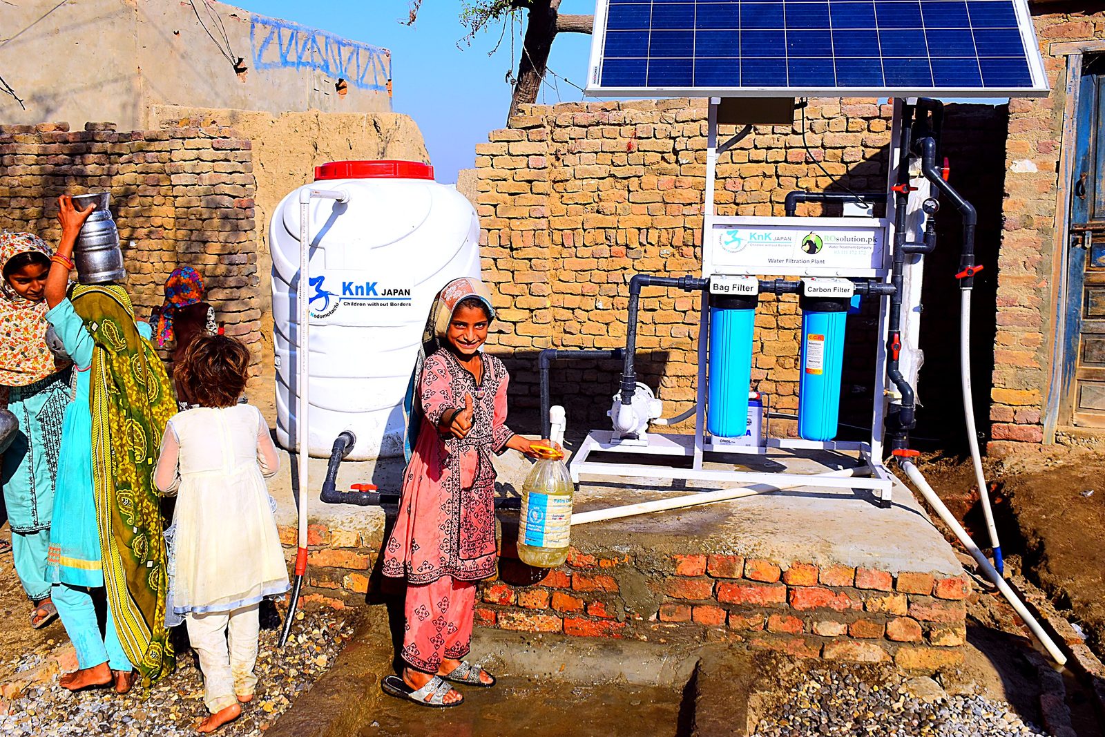 A girl fills a bottle with clean water at a solar-powered filtration plant